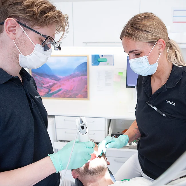 En tandlaege og en klinikassistent sammen med en patient i en tandlaegestol